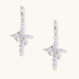 White gold-plated hoop earrings with sparkling zirconia cross charms dangling against cream background