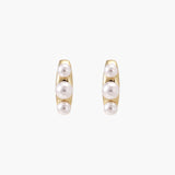 14K gold-plated curved stud earrings with three white freshwater pearls aligned vertically on cream background