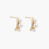 14K gold-plated curved stud earrings with three white freshwater pearls aligned vertically on cream background