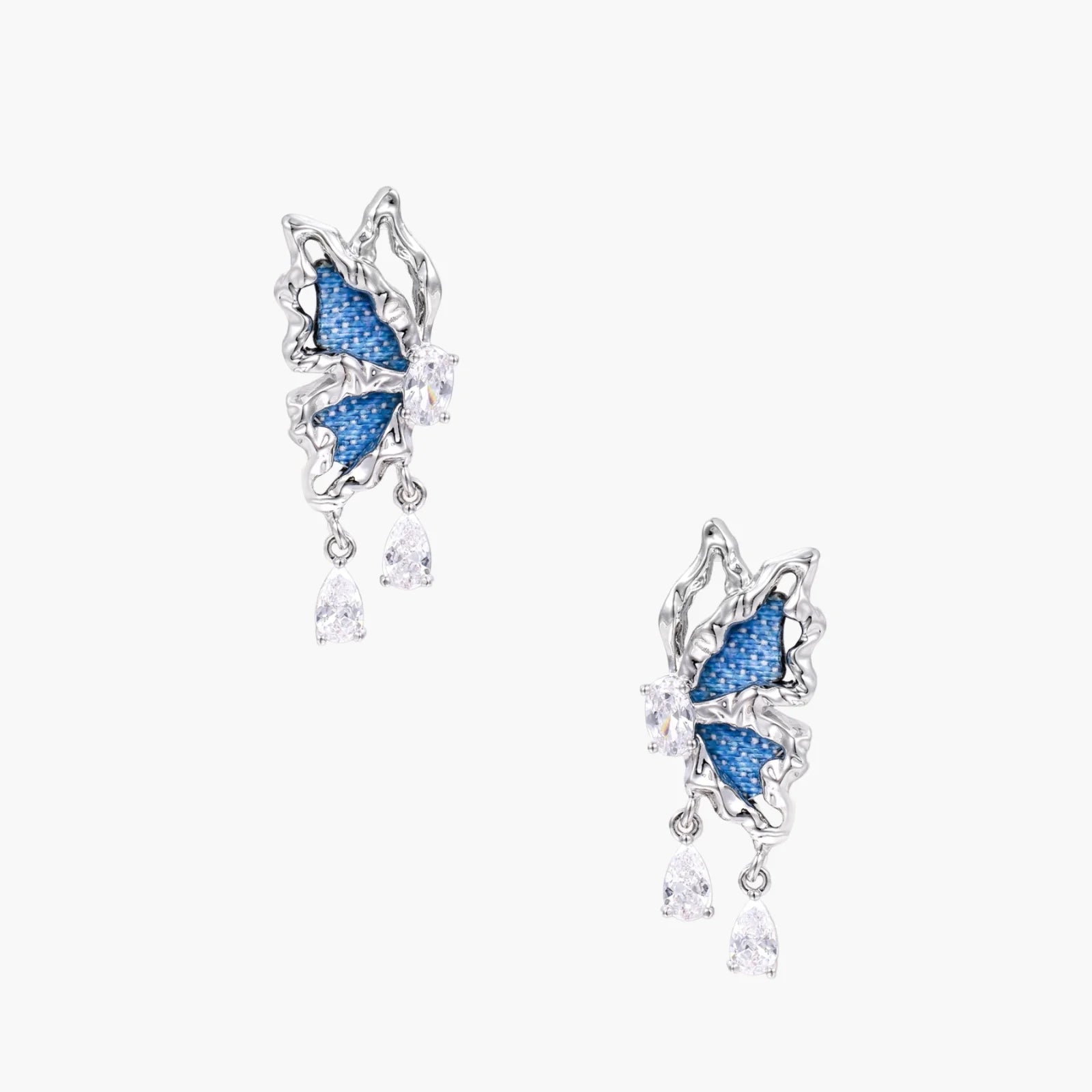 Silver butterfly earrings with blue denim fabric wings and dangling teardrop crystals on cream background