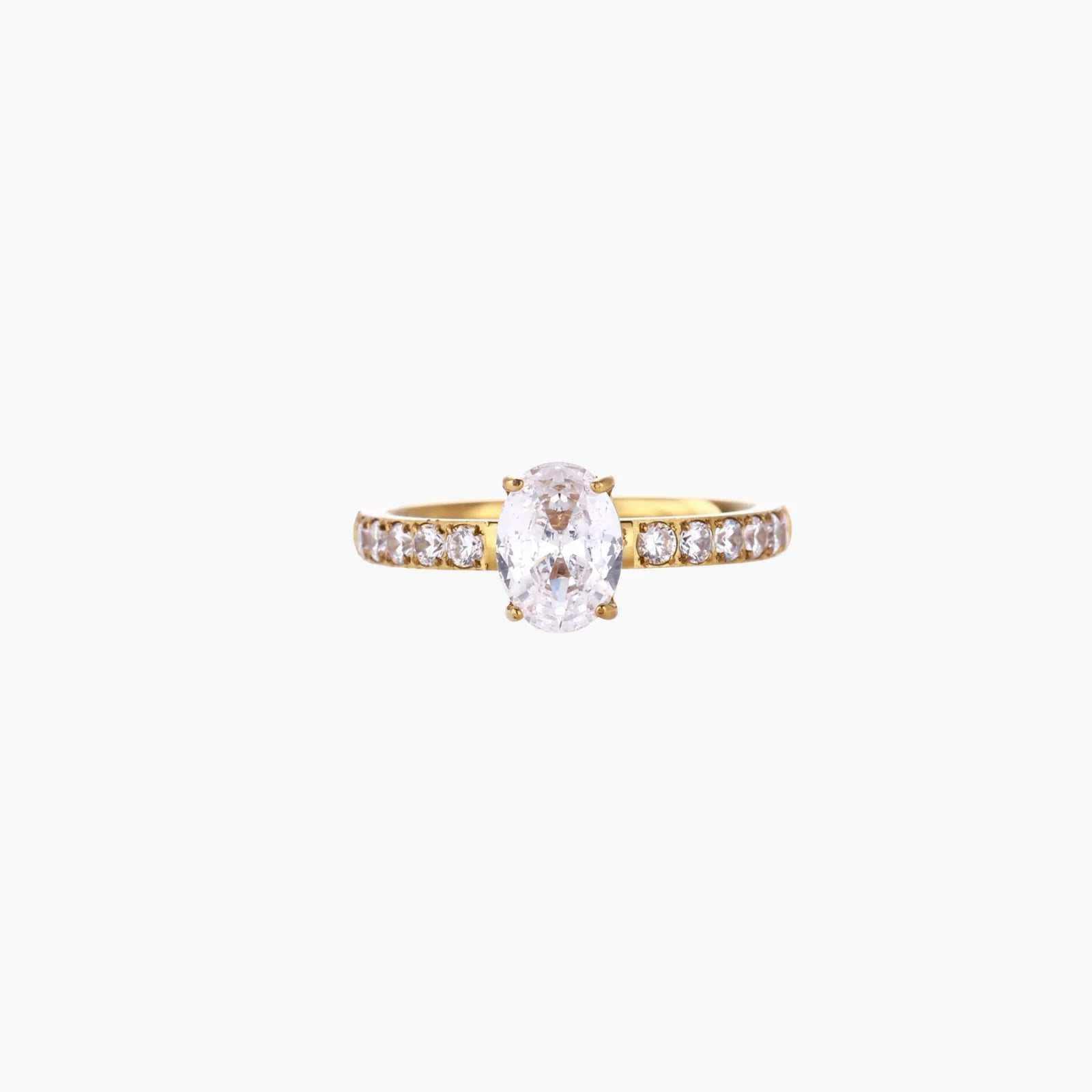 Gold-plated solitaire ring with oval zirconia center stone and pavé band on cream background