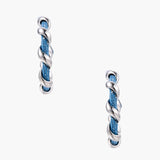 White gold-plated hoops intertwined with blue denim fabric in a twisted rope design on cream background.