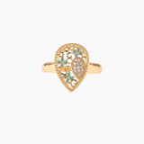 Teardrop-shaped gold-plated ring with turquoise enamel flowers and crystal pavé detail on cream background