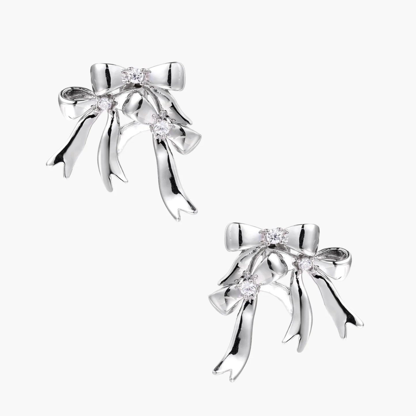 Sculptural bow earrings in polished white gold plate with sparkling zirconia stones and flowing ribbon details