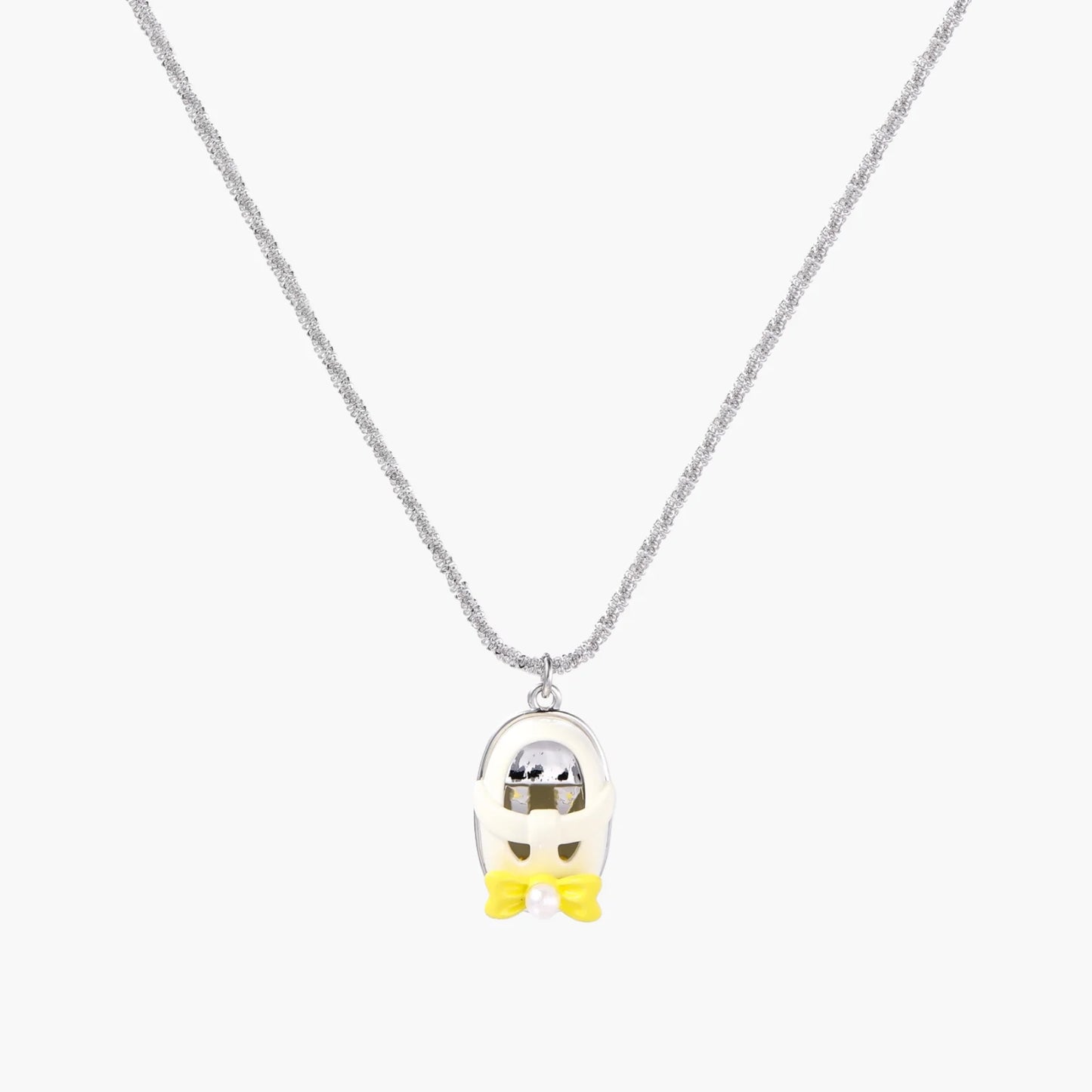 Chrome egg-shaped pendant with kawaii face, yellow bow, and pearl detail on silver chain against white background