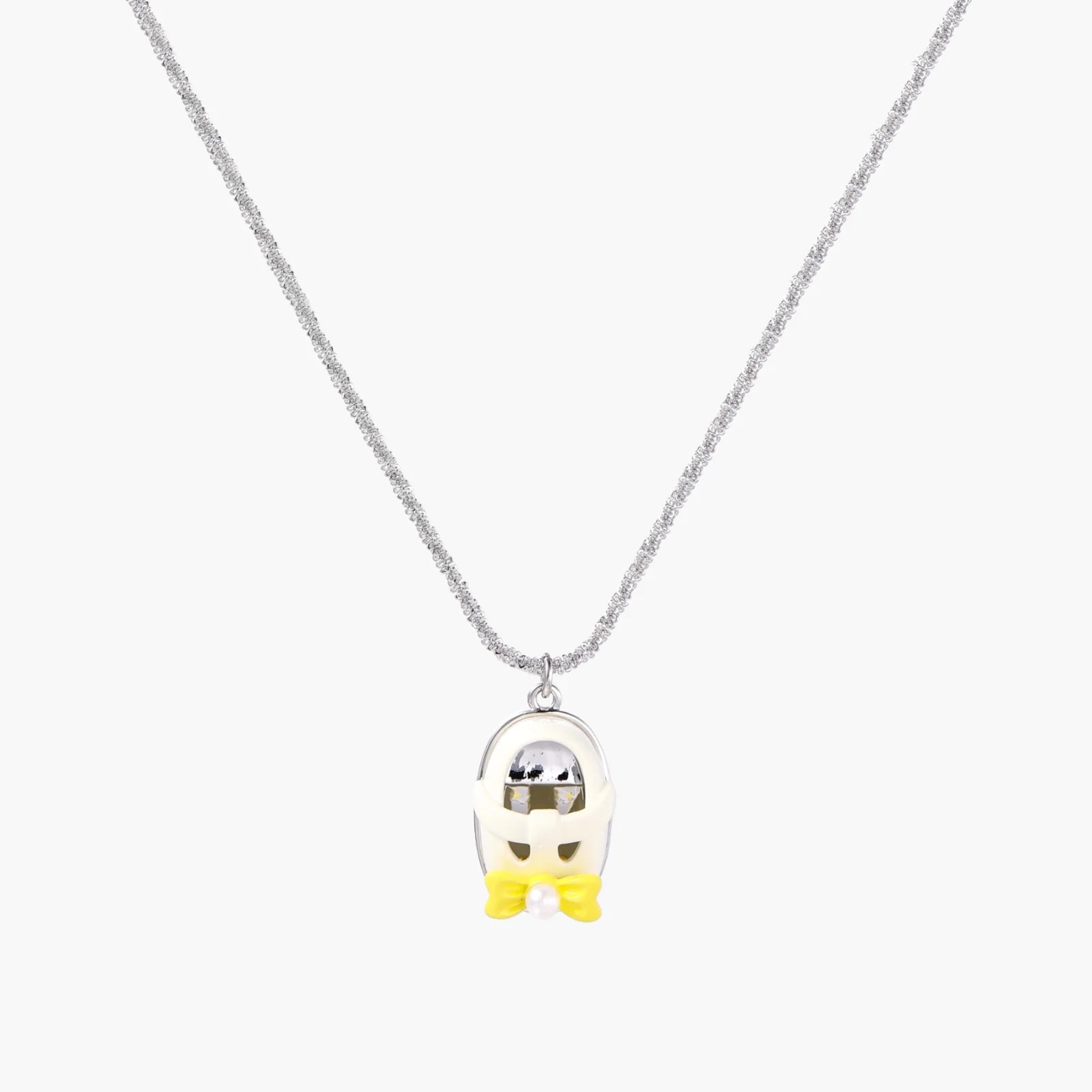 Chrome egg-shaped pendant with kawaii face, yellow bow, and pearl detail on silver chain against white background