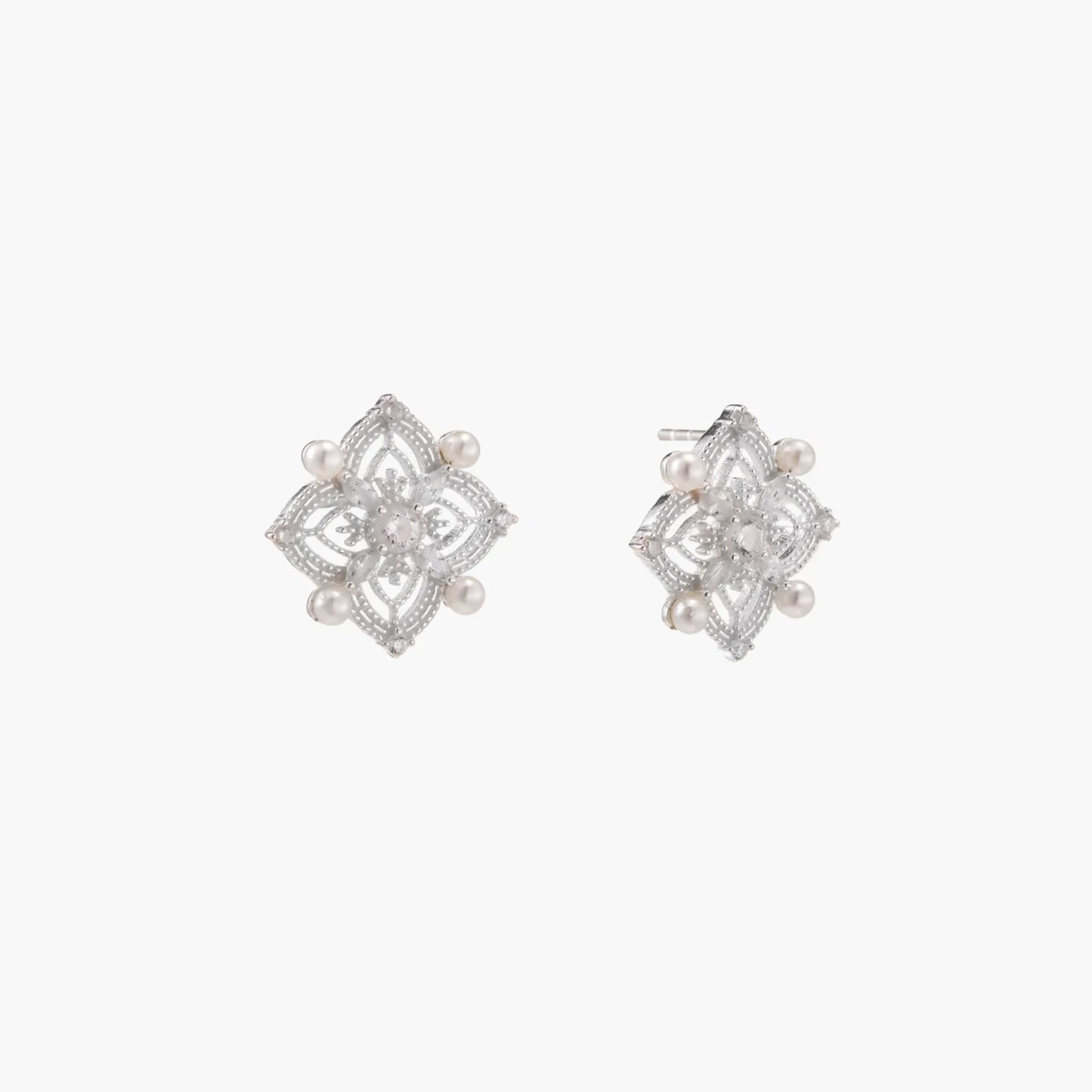 Ornate sterling silver stud earrings with mandala-inspired filigree pattern and four freshwater pearls on beige background