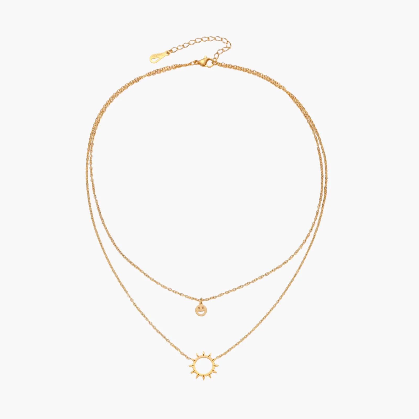 Gold layered necklace set with sunburst and smiley face pendants on delicate chains against white background.