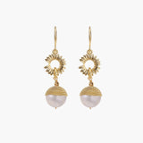 Gold sunburst charm earrings with baroque pearl drops on French hooks against cream background