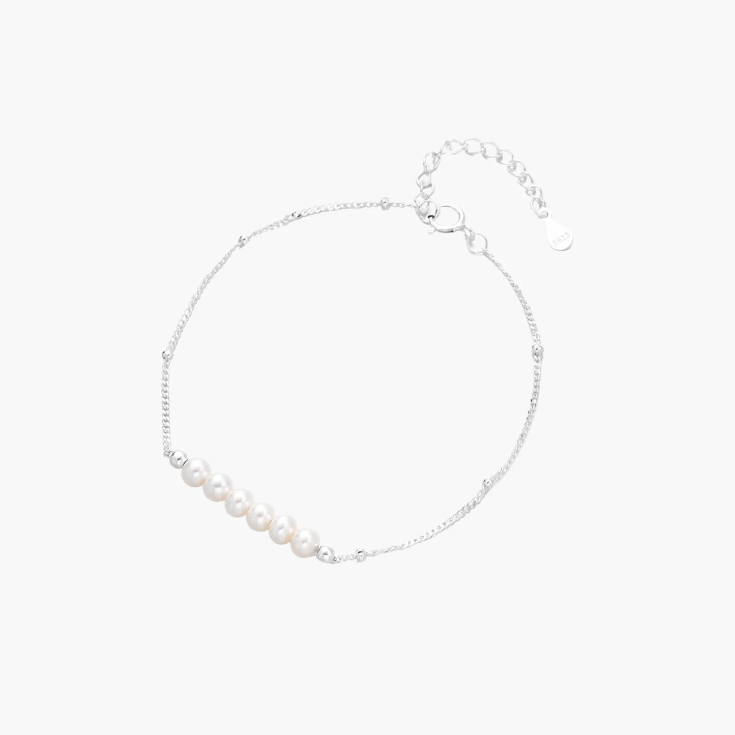 Delicate rhodium-plated silver chain bracelet with row of small baroque pearls centered on white background.
