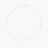 Delicate sterling silver chain necklace with small freshwater pearls arranged in a curved smile arc on cream background.