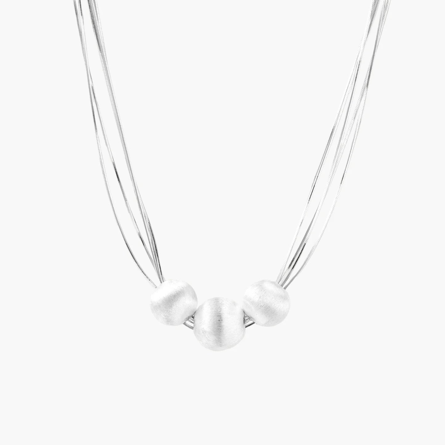 Sterling silver multi-strand necklace with three brushed round beads on cream background