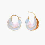 Shell-shaped hoop earrings with iridescent blue-pink enamel and gold trim on cream background