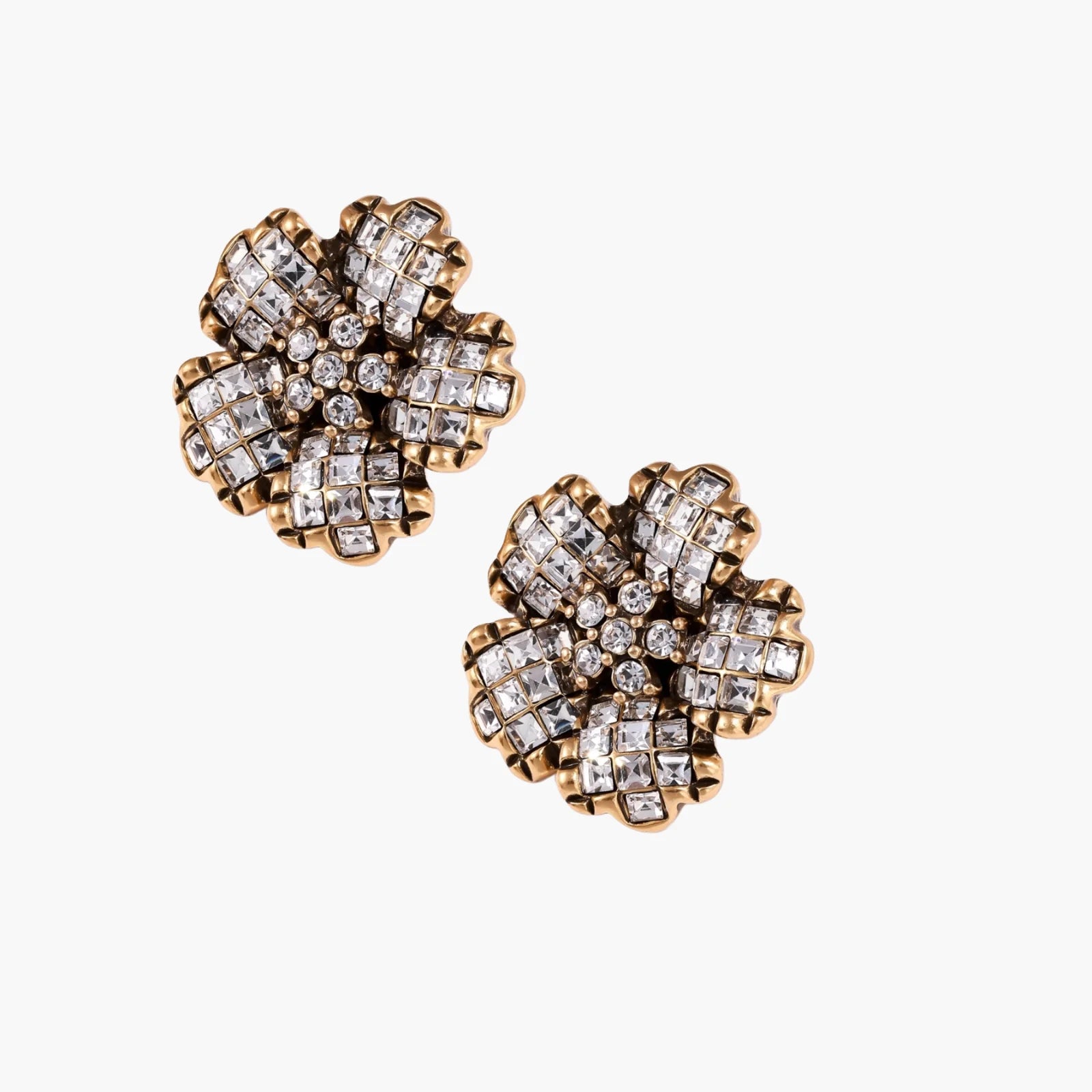 Gold-plated floral stud earrings with geometric zirconia crystals arranged in five-petal design on cream background