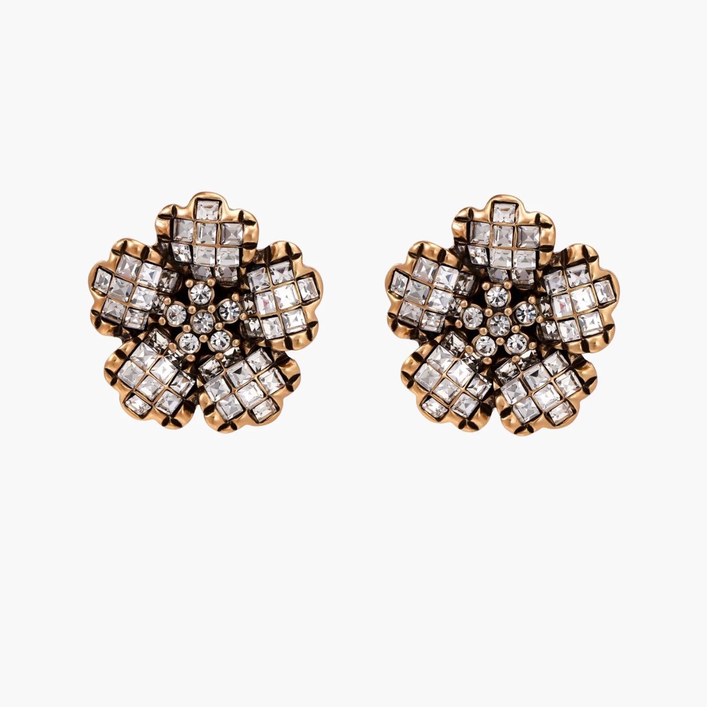 Gold-plated floral stud earrings with geometric zirconia crystals arranged in five-petal design on cream background
