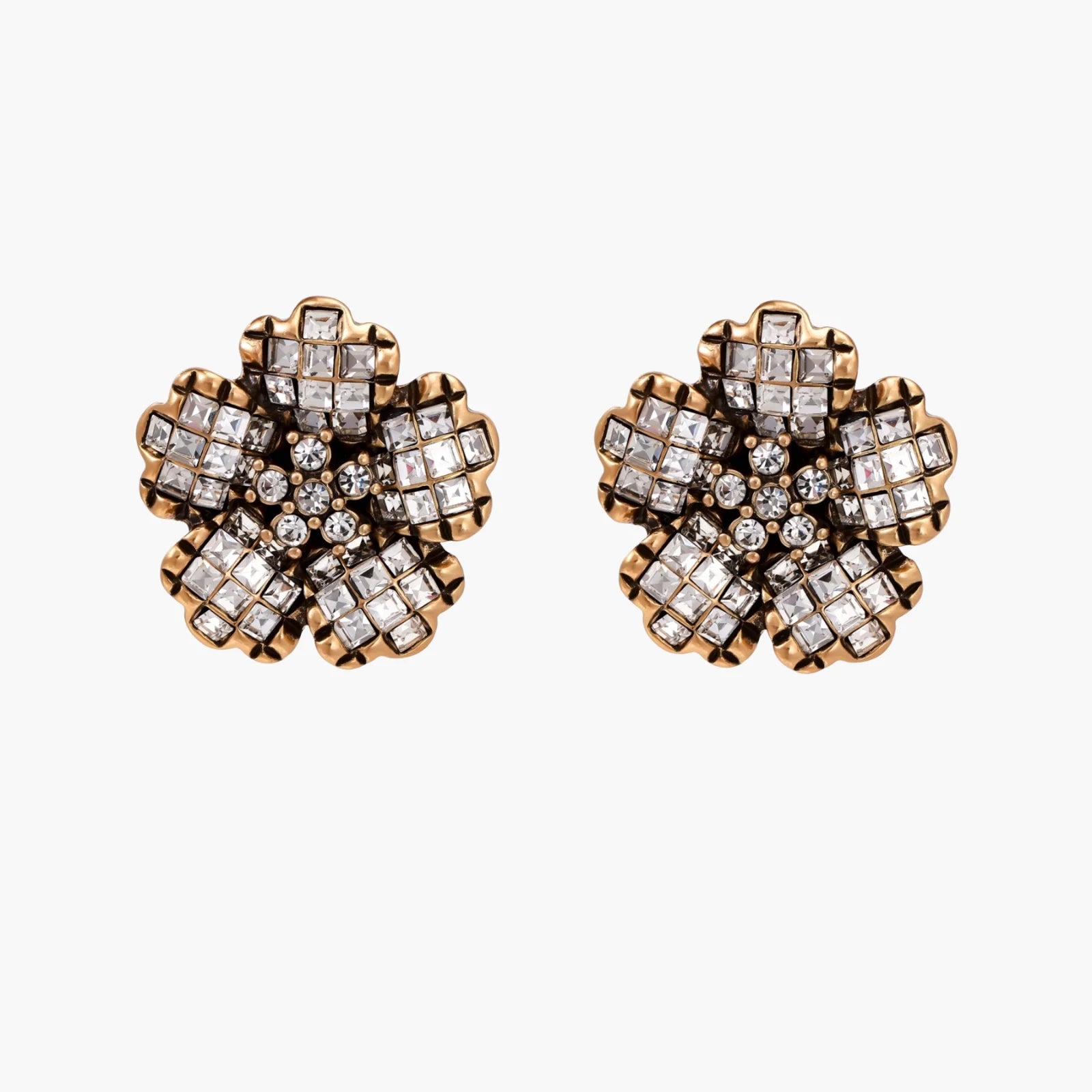 Gold-plated floral stud earrings with geometric zirconia crystals arranged in five-petal design on cream background