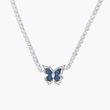 White gold plated tennis necklace with blue denim butterfly pendant and clear zirconia stones on cream background
