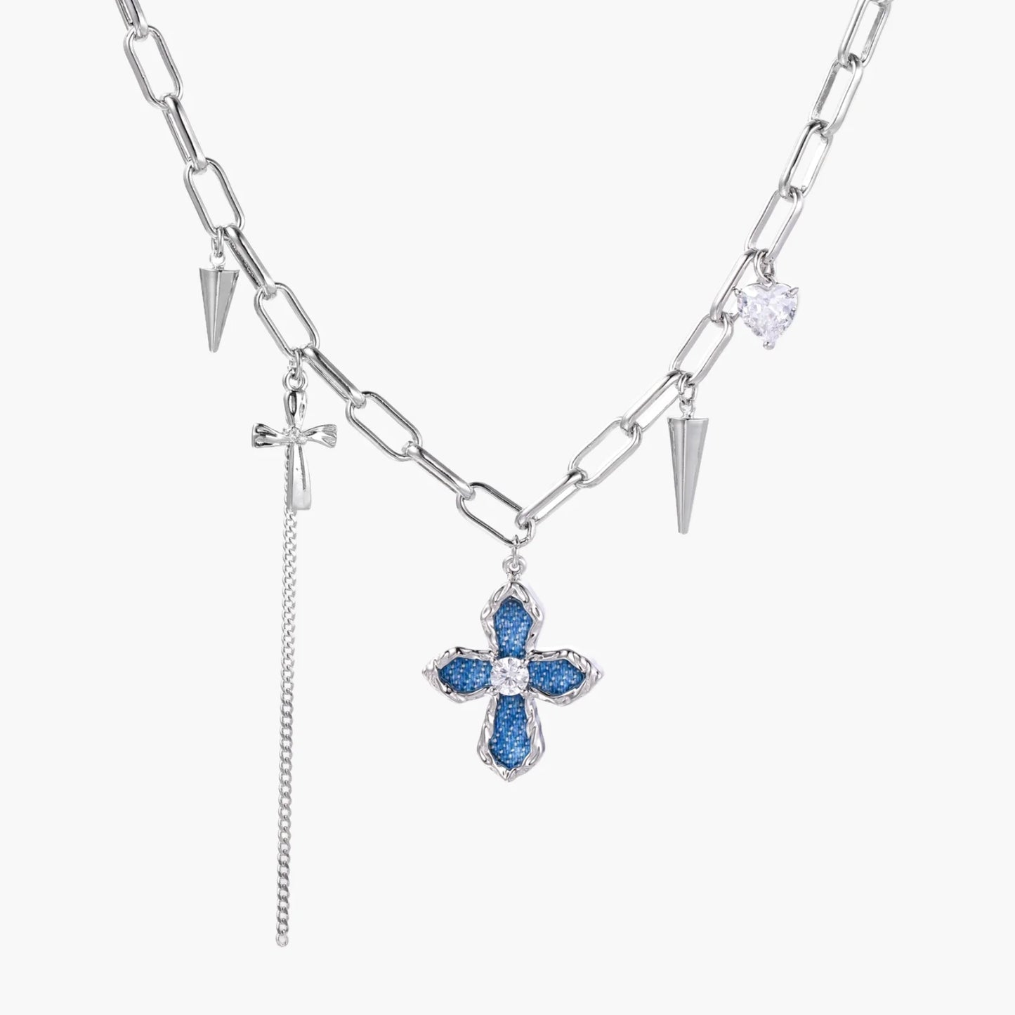 White gold plated chain necklace with blue textured cross pendant, spike charms, and mini cross detail on beige background