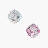 Silver unicorn stud earrings with pastel blue and pink enamel stones in sunburst prong settings on cream background