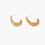 Curved gold hoop earrings with raised granulated texture resembling sea urchin surface on cream background